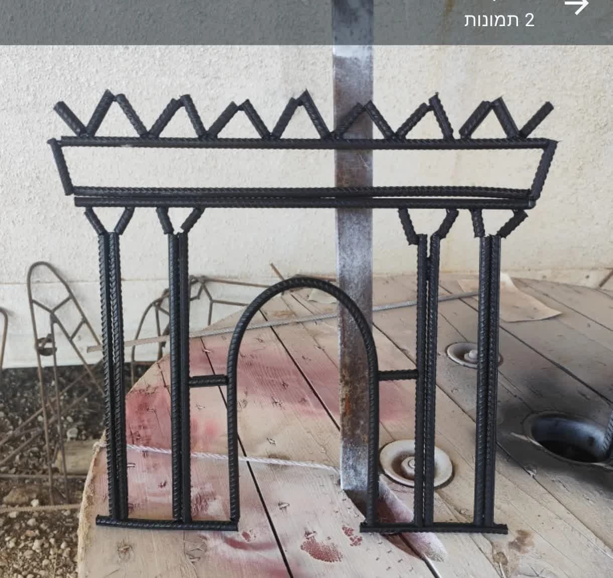 Custom work — iron sculpture in the form of a structure, on a round wooden surface in the studio